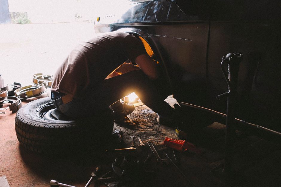A dedicated mechanic intensely focused on repairing a car wheel in an auto repair shop.